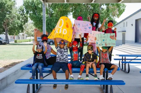 Kids on Picnic Table in Costumes with No Kid Hungry Signs